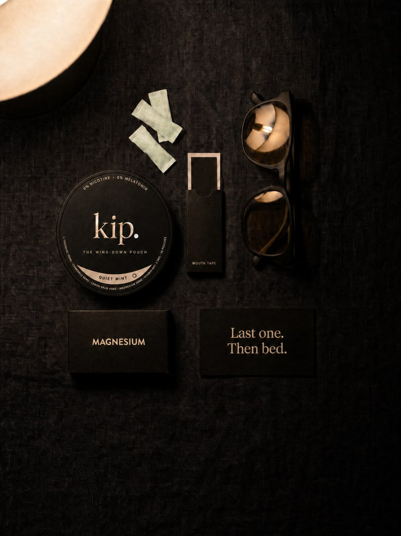 The kip wind-down kit laid out on dark linen: the Quiet Mint tin, mouth tape, a card reading Last one. Then bed.