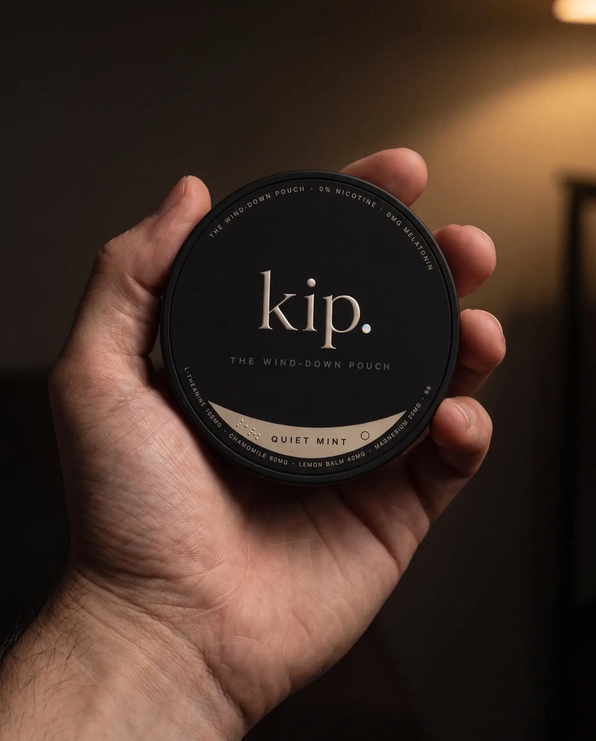 A hand holding a kip tin in lamplight